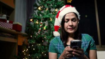 feliz mulher às casa conectando com dela Smartphone em Natal dia video