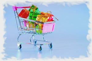 Trolley with New Years gifts on blue in snow frame photo