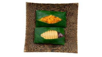 Thai desserts served on coconut plates wrapped in banana leaves. Coconut Flavored Sticky Rice with Dried Fish and Sugar and Sweet Sticky Rice blackk with Thai Custard. Isolated white background. photo