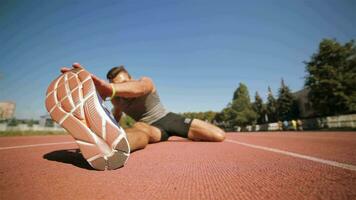 masculino atletismo estiramientos su pierna a el estadio video