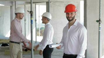 masculino constructor sostiene conjunto de planes de edificio debajo construcción video