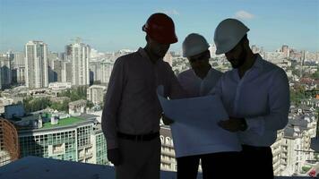 Three builders examine the project of building under construction video