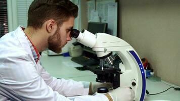 hombre mirando mediante el microscopio a el laboratorio video