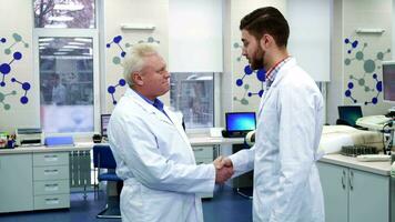 dois masculino cientistas cumprimentar cada de outros às a laboratório video