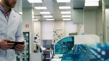 Man checks the work of lab device with tablet video