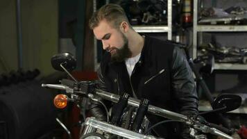 Male biker examines the chopper at the motorcycle workshop video