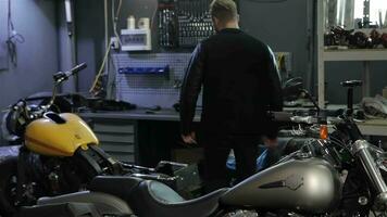 masculino motorista desenrosca alguna cosa en el motocicleta por el llave inglesa video