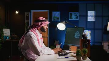 Licensed arabic engineer updating neural networks, writing intricate binary code scripts on computer. Middle Eastern man uses digital device programming to upgrade AI datasets at home video