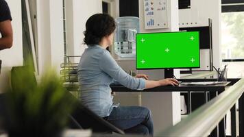 Office worker checks greenscreen monitor at desk, working on business operations with blank copyspace template on computer desktop. Person typing information and examining isolated mockup. video