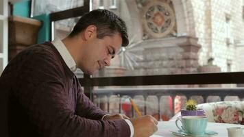 Man writes in his notebook at the cafe video