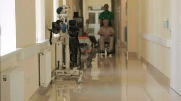 médico empuja silla de ruedas con paciente a el hospital video