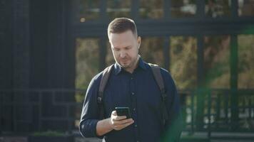 modern urban man användningar en smartphone på en stad gata. internet teknik göra den lättare till tillgång olika tjänster och assistenter använder sig av mobil applikationer. video