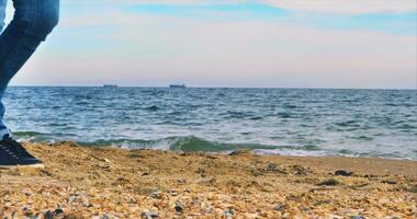 A girl with a white manicure collects shells on the shore of the Black Sea in clear weather video