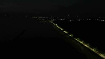 aéreo ver de un abandonado calle a noche. aéreo ver de un fila de calle luces en el borde de lago limbo, gorontalo-indonesia video