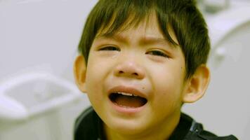 detailopname van een weinig jongen huilen terwijl zittend Aan de toilet. video