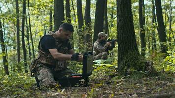 A Soldier Prepares the Drone for Flight While Colleague Guards Him in the Forest video