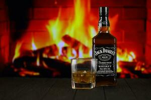 KYIV, UKRAINE - MAY 4, 2022 Jack Daniels original alcohol bottle on wooden table with red fireplace photo