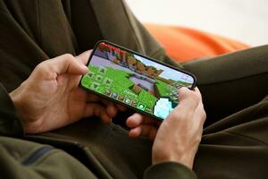 Minecraft mobile iOS game on iPhone 15 smartphone screen in male hands during mobile gameplay photo
