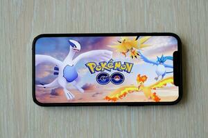 Pokemon GO mobile iOS game on iPhone 15 smartphone screen on wooden table during mobile gameplay photo