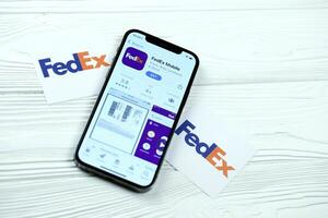 KHARKOV, UKRAINE - MARCH 5, 2021 Fedex icon and application from App store on iPhone 12 pro display screen on white table photo