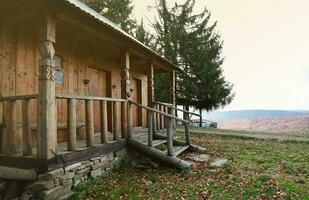 Small wooden house among trees and mountains in the middle of nature on an autumn photo