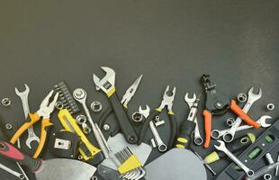 Handyman tool kit on black wooden table. Many wrenches and screwdrivers, pilers and other tools for any types of repair or construction works. Repairman tools photo