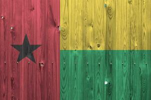 Guinea Bissau bandera representado en brillante pintar colores en antiguo de madera pared. texturizado bandera en áspero antecedentes foto