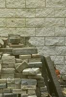 A large pile of disassembled paving tiles against the wall of light bricks photo