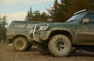 Automobile in a countryside landscape with a mud road. Off-road 4x4 suv automobile with ditry body after drive in muddy road photo