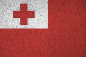 Tonga flag depicted in bright paint colors on old relief plastering wall. Textured banner on rough background photo