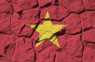 Vietnam flag depicted in paint colors on old stone wall closeup. Textured banner on rock wall background photo