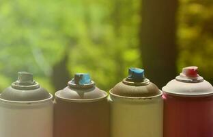 A few used aerosol paint sprayers lie on the windowsill in the workshop of a graffiti artist. The concept of street art and illegal drawing on the walls. Youth hobby photo