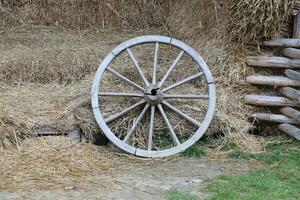 Place with stacks of hay cubes and rustic wooden wheels of old cart photo