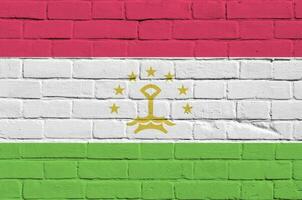 Tajikistan flag depicted in paint colors on old brick wall. Textured banner on big brick wall masonry background photo