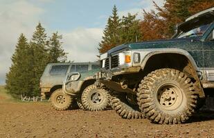 Automobile in a countryside landscape with a mud road. Off-road 4x4 suv automobile with ditry body after drive in muddy road photo