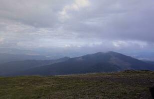 Morning view from the Dragobrat mountain peaks in Carpathian mountains, Ukraine. Cloudy and foggy landscape around Drahobrat Peaks photo