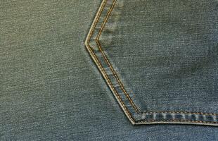 Detailed abstract texture of dark blue denim cloth. Background image of old used denim trousers fabric photo