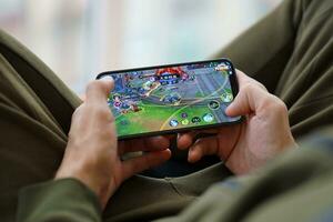 Honor of Kings mobile iOS game on iPhone 15 smartphone screen in male hands during mobile gameplay photo