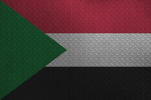 Sudan flag depicted in paint colors on old brushed metal plate or wall closeup. Textured banner on rough background photo