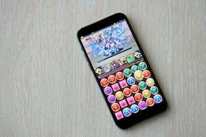 Puzzle and dragons mobile iOS game on iPhone 15 smartphone screen on wooden table during mobile gameplay photo