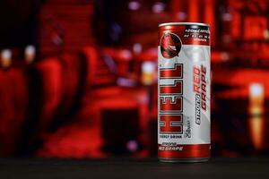 KHARKOV, UKRAINE - FEBRUARY 14, 2021 Hell energy drink can on black wooden table with red interior background photo