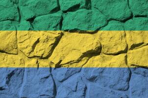 Gabon flag depicted in paint colors on old stone wall closeup. Textured banner on rock wall background photo