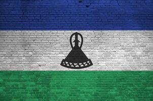 Lesotho flag depicted in paint colors on old brick wall. Textured banner on big brick wall masonry background photo