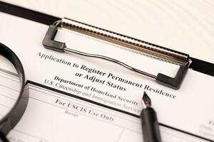 I-485 Application to register permanent residence or adjust status blank form on A4 tablet lies on office table with pen and magnifying glass photo