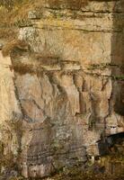 Light coarse natural rock stone background. Mining cliff rough front surface. Big limestone stack backdrop. Heavy grunge damaged granite block texture photo