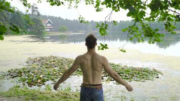 giovane uomo felicemente raccolta il suo mani di il lago. video