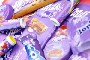 KHARKOV, UKRAINE - JULY 2, 2021 Milka chocolate products with classical lilac color wrapping design on white table photo