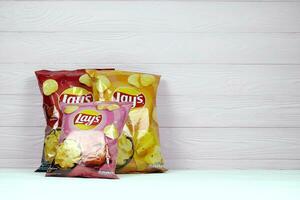 KHARKOV, UKRAINE - JANUARY 3, 2021 Various flavoured of lay's potato chips on wooden background. Lay's has been owned by PepsiCo through Frito-Lay in 1965 photo