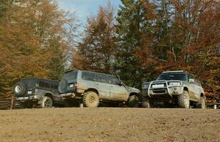 Automobile in a countryside landscape with a mud road. Off-road 4x4 suv automobile with ditry body after drive in muddy road photo