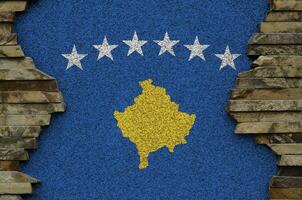 Kosovo bandera representado en pintar colores en antiguo Roca pared de cerca. texturizado bandera en rock pared antecedentes foto